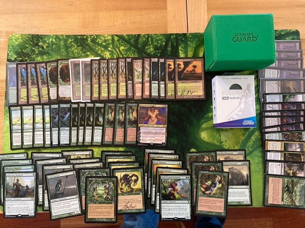 Paper version of Elves cards from Magic: The Gathering, green Katana sleeves and green Sidewinder deck box from Ultimate Guard laid out on Forest playmat