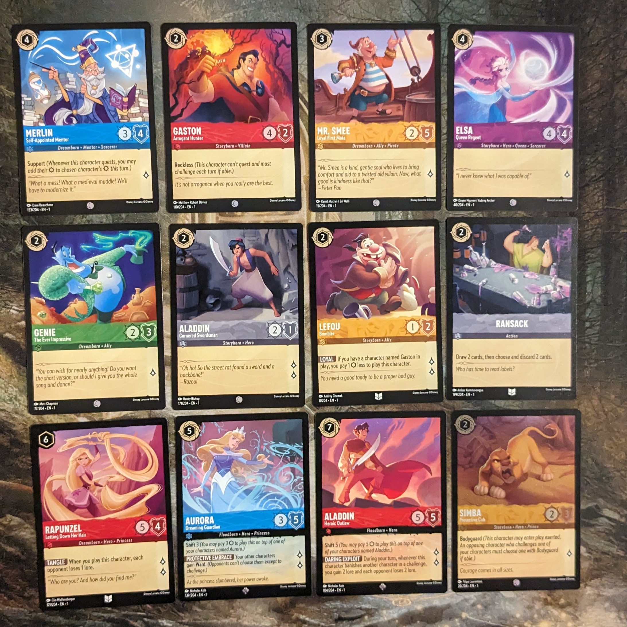 Merlin, Gaston, Dr. Smee, Elsa, Geenie, Aladdin, Lefou, Ransack, Rapunzel, Aurora, Simba cards from Disney Lorcana