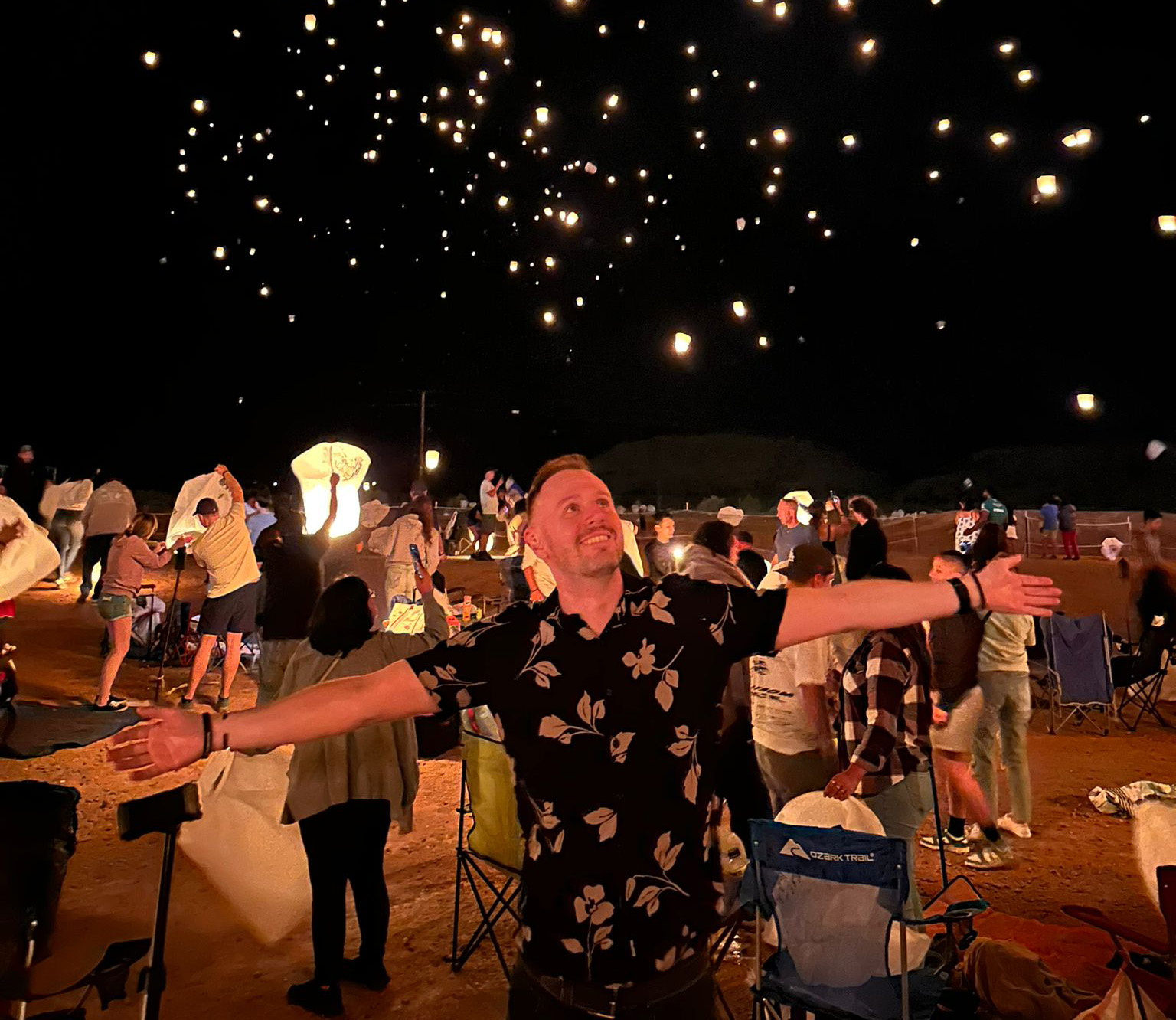 Photo of Matt Abrams spreading his arms with lanterns in the background