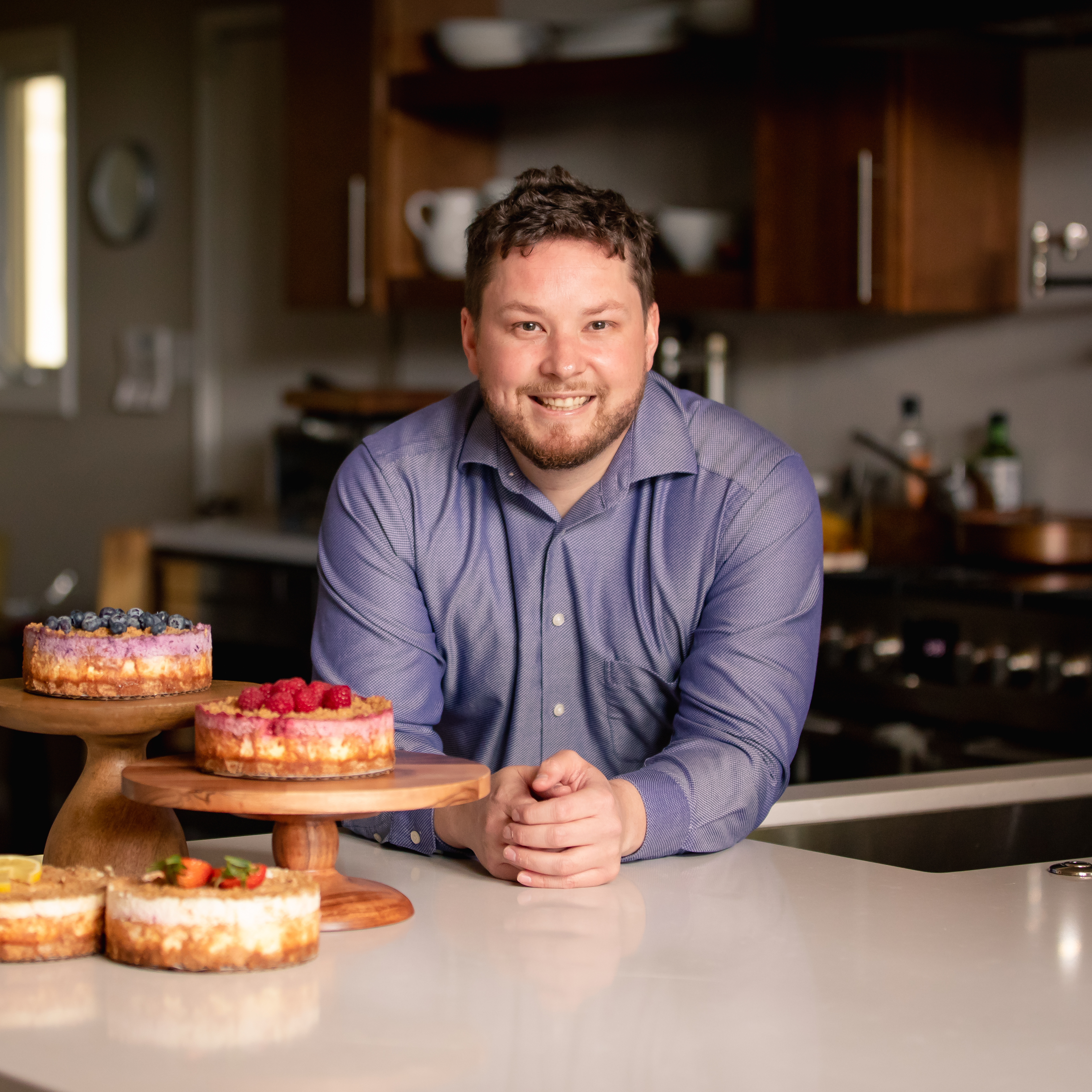 Photo of Chris Bruner in kitchen with 3 cakes to his left