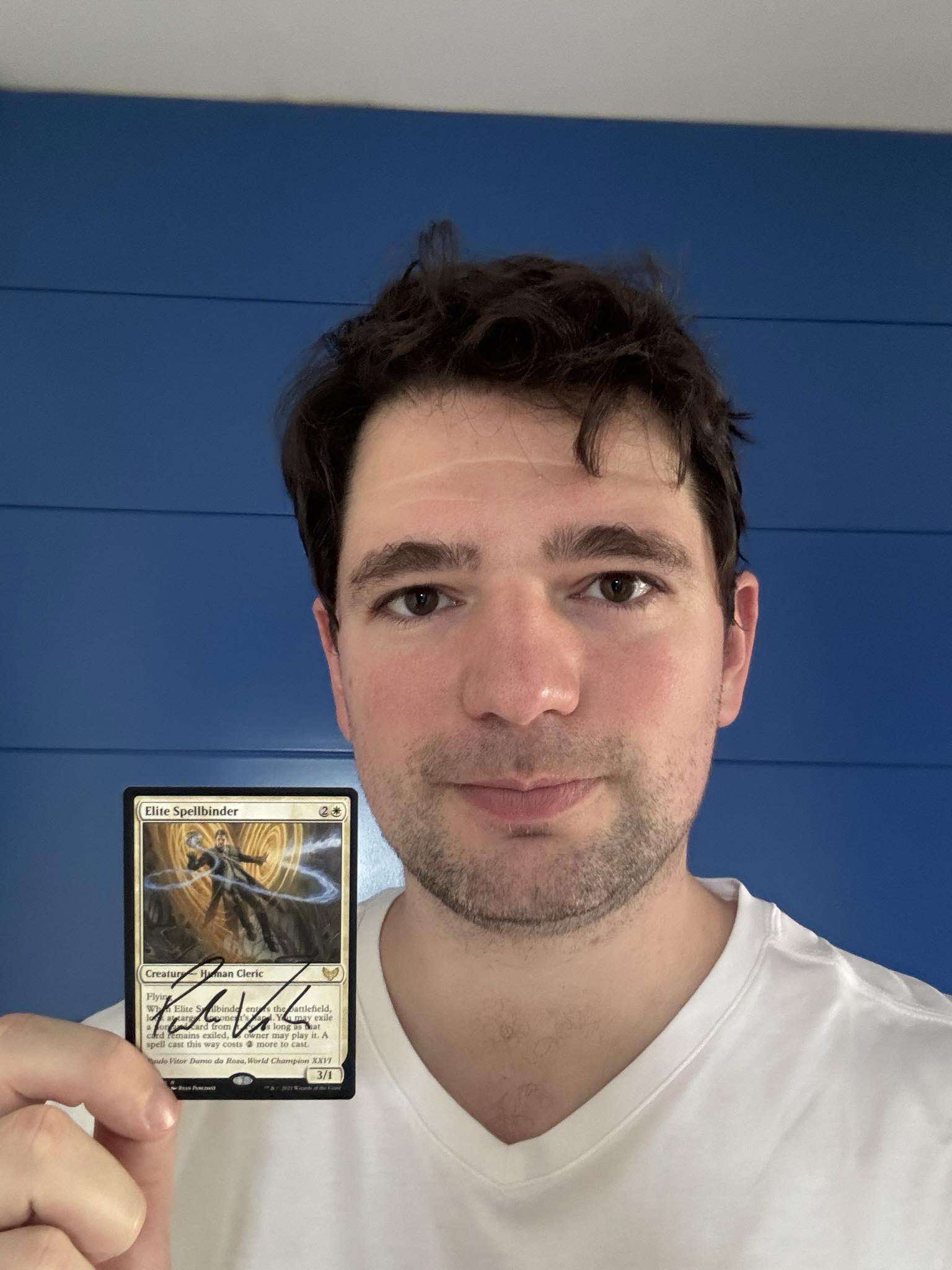 Paulo Vitor Damo da Rosa holding signed Elite Spellbinder Card from Magic: The Gathering