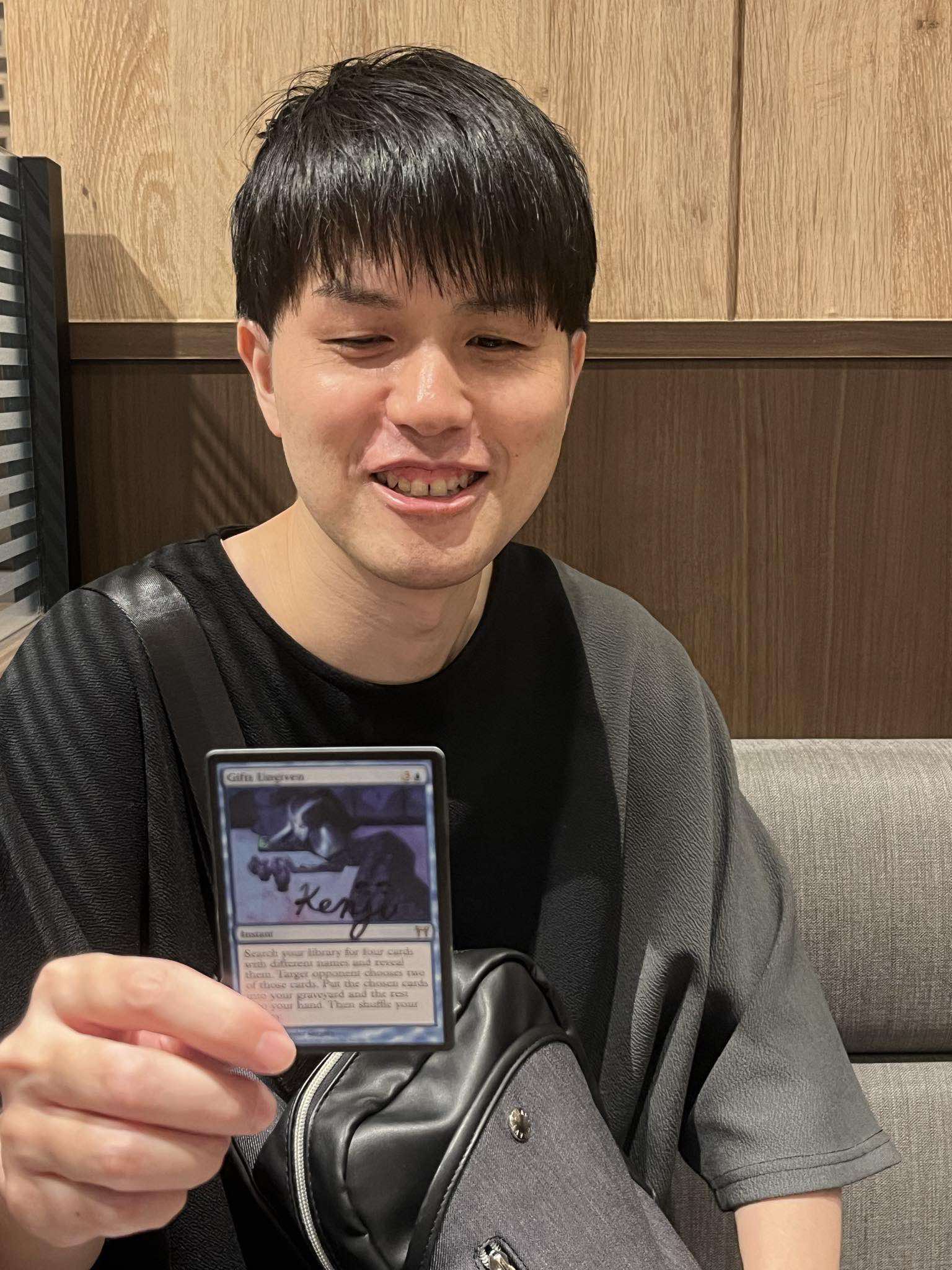 Kenji Tsumura holding signed Gifts Ungiven Card from Magic: The Gathering